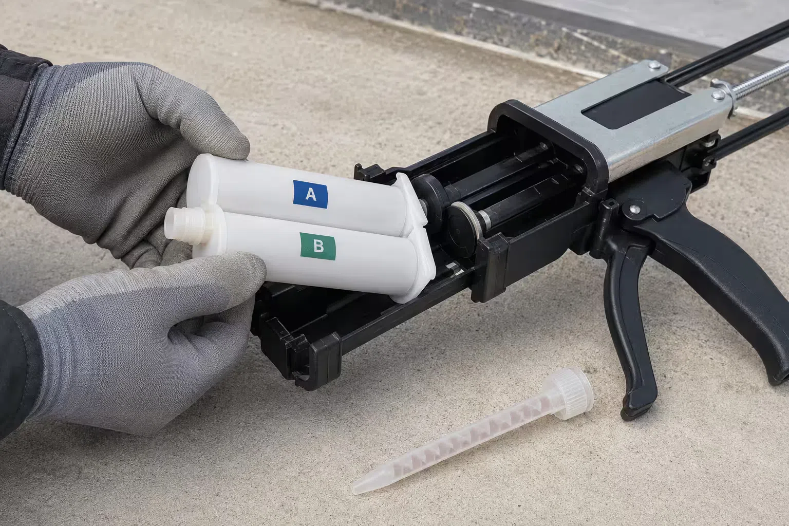 A 200ml dual cartridge being loaded into a manual gun with the cartridge holder open, showing how the A and B cartridges sit side by side before the holder closes and locks