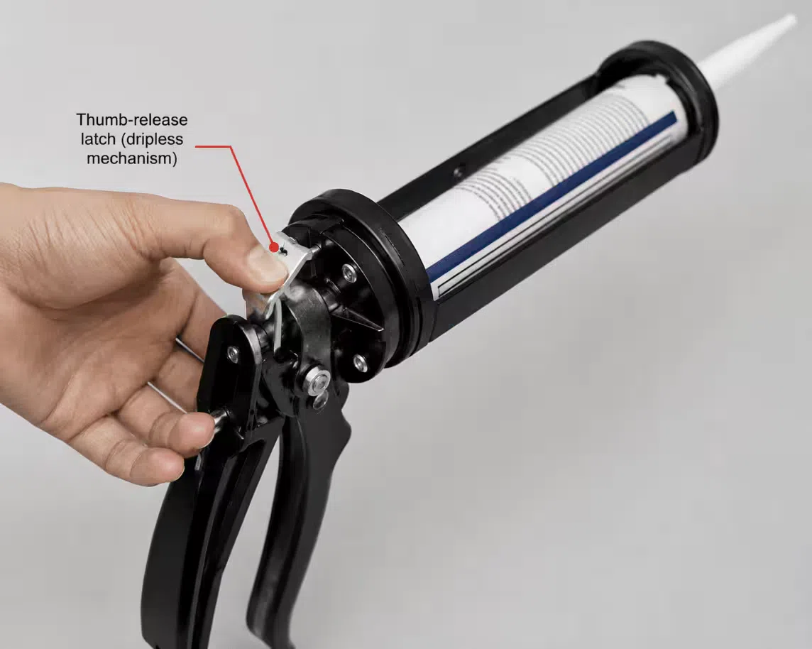 Hand operating the thumb-release latch on a manual caulking gun dripless mechanism, nozzle pointed away from the work surface