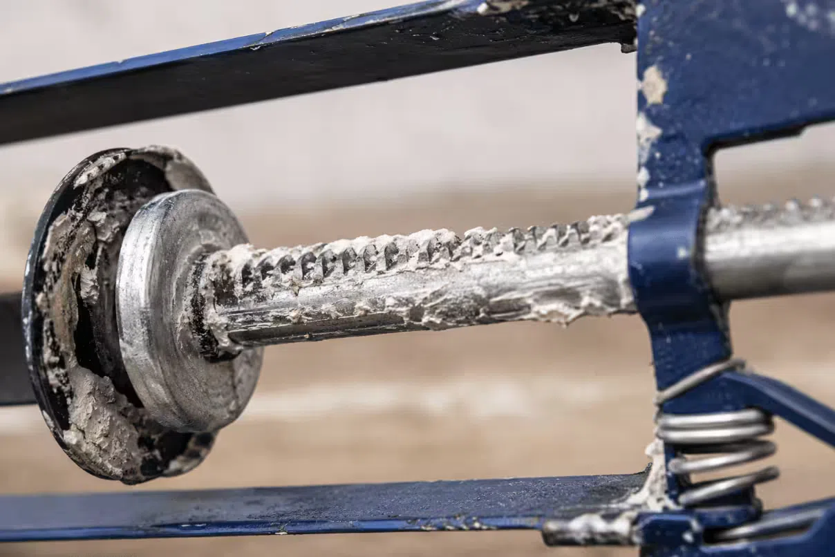 Close-up view of dried sealant buildup on a manual caulking gun plunger rod causing sticking during use
